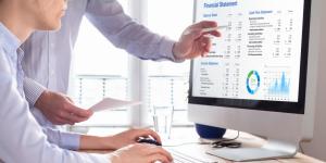 Quickbooks Online and Best Accounting Practices for Small Businesses Two people at a desk with a computer looking over a financial statement