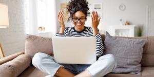 Happy african american young woman using her laptop in her living room