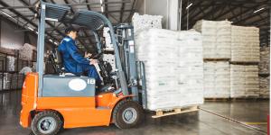 A man on a forklift works in a large warehouse