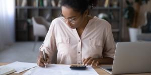 Woman sits at desk calculating expenses