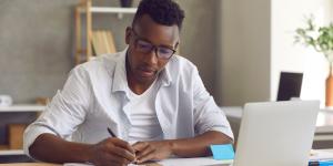 Young african american writing in a notebook