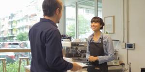 Happy latin barista in apron collecting an order