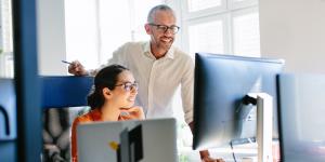 How To Launch a Partner Program: 9 Partnership Considerations Older man and young woman looking at computer and smiling