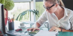 Woman at desk working with financial paperwork Woman at desk working with financial paperwork