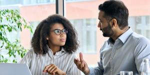 10 Mistakes to Avoid When Hiring Your First Sales Team older Indian man and younger woman of color looking at laptop together