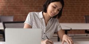 How to Create a Mission Statement and Why Startups Need One asian woman writing on paper while at her computer