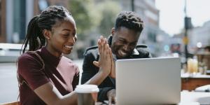 How To Work More Efficiently: 11 Tips From Entrepreneurs two young black entrepreneurs working at a computer and high fiving each other