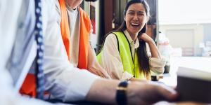 How to Manage Reputation and Competitive Risk young asian woman laughing with coworker while wearing yellow reflective work vest