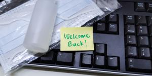 The Post-Pandemic Workplace: 3 Options To Consider black keyboard with hand sanitizer and yellow sticky note saying welcome back