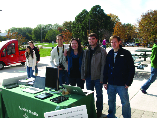 An image of four people standing in front of a table.