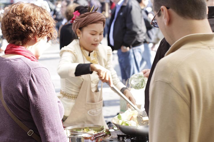 May Kaidee serving food to customers at cooking demonstration in Union Square, New York City.
