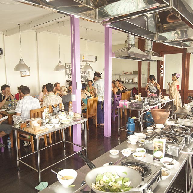 Students sitting and eating a freshly cooked recipe inside of our Bangkok cooking school.