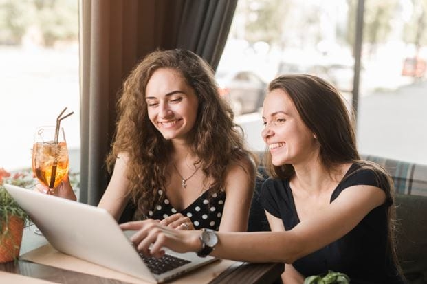 Chamada para artigos: imagem de duas mulheres olhando para um notebook.