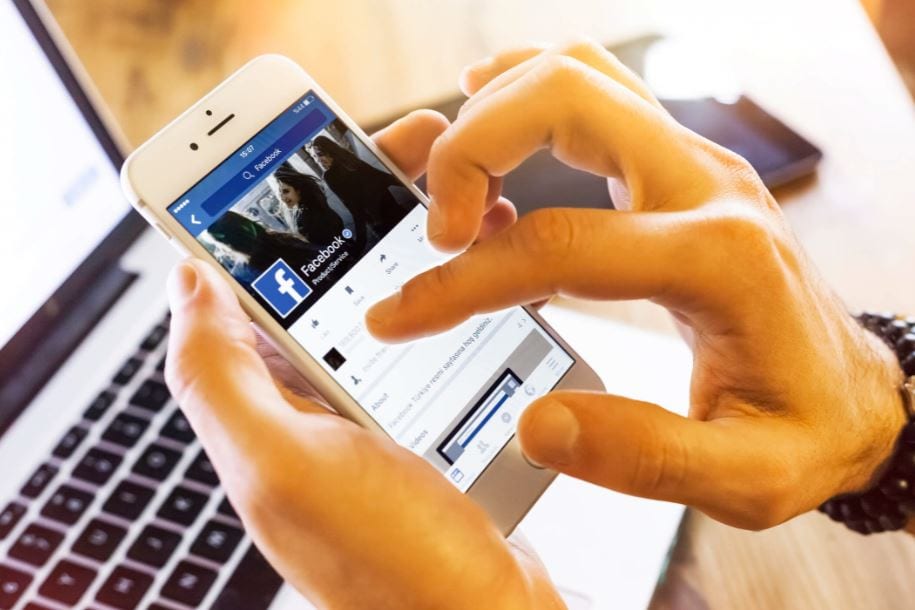 Alcance orgânico no Facebook: imagem de uma pessoa mexendo no Facebook pelo celular