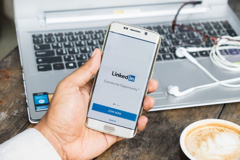Sales Navigator: imagem de uma mão segurando um celular com a tela do LinkedIn aberta.