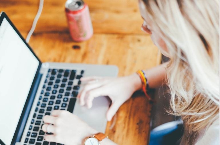 Canva online: imagem de uma mulher loira digitando no notebook.