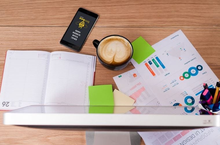 Campanha de Marketing: imagem de uma mesa com anotações em papéis (gráficos, contas) uma xícara de café e um computador.