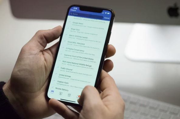 Como desativar comentários no Facebook: imagem de duas mãos segurando um celular com a tela do facebook aberta nos comentários