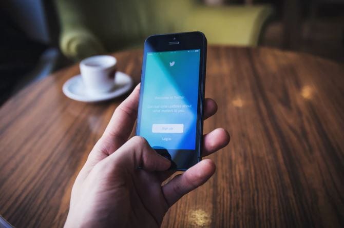 Twitter Ads: imagem de uma mão segurando um celular com a tela do twitter aberta