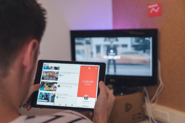 Ganhar visualizações no YouTube: imagem de um homem com um tablet nas mãos procurando vídeos no YouTube .