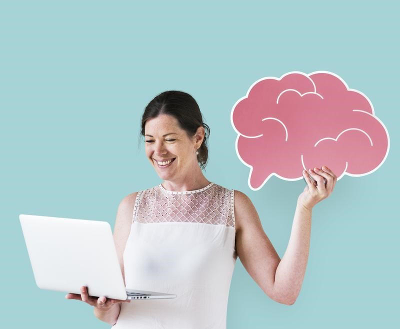 Como criar um logo: imagem de uma mulher segurando um notebook com uma mão olhando para a tela e segurando um cérebro desenhado na cor rosa na outra mão.