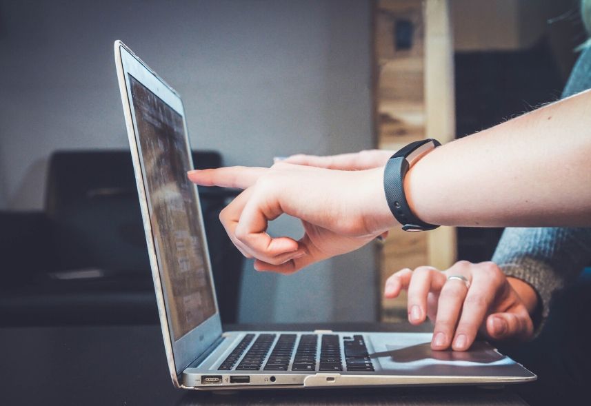 Planejamento de mídia: imagem de um notebook aberto em cima de uma mesa e duas mãos apontando para tela