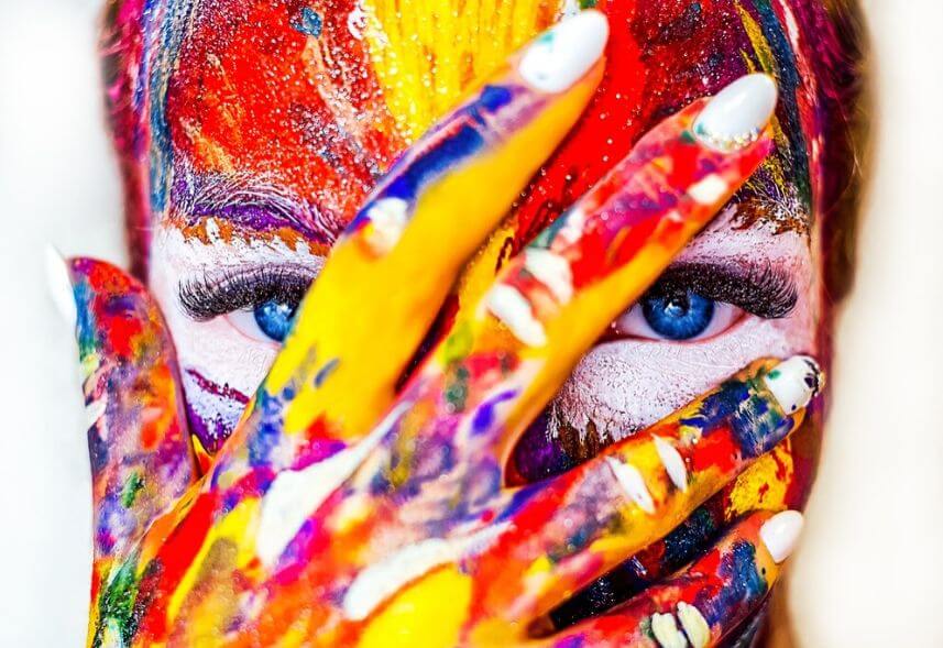 Cores no Marketing: imagem do rosto de uma mulher todo pintado de tinta com as cores azul, amarela, vermelho