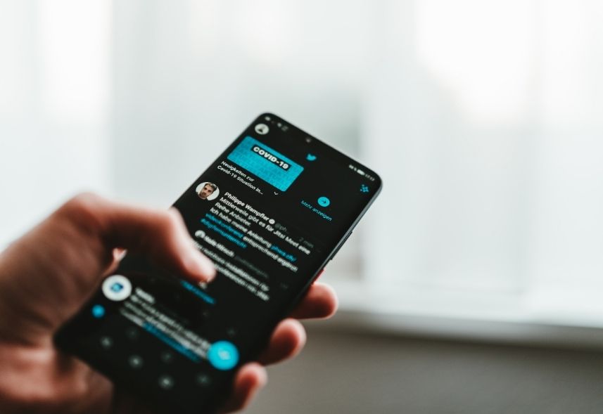 o que é engajamento no twitter: imagem de uma mão segurando o celular mexendo no twitter