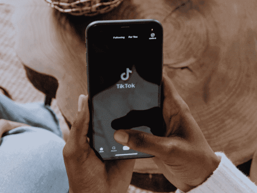 TikTok para empresas: uma mão está segurando um celular, na tela é possível ver o ícone e o nome do aplicativo "TikTok".