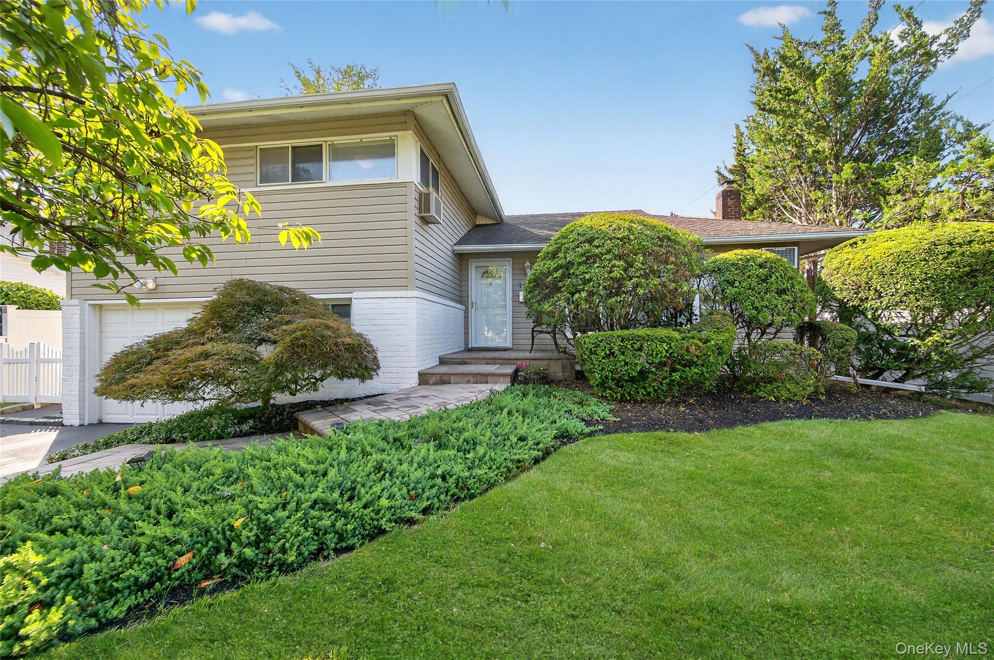 This lovely, updated, sun-flooded split level home is set in a quiet neighborhood location. The entry foyer leads into the formal living room, with a wall of windows, and is open to the dining room with sliders out to the large, private deck and beautifully landscaped yard. The eat-in kitchen features updated white cabinetry, huge pantry closet, stainless steel appliances and tile flooring. Take a few steps down to the spacious den and super private home office. There is an door to the garage and take more steps down to the partially finished basement with great storage, laundry room, rec room and utilities. On the bedroom level are three bedrooms, including a king sized primary bedroom with ceiling fan, full wall of closet space and updated full bath with shower. The main hall bath has a skylight and is beautifully updated and fully tiled. All bedrooms have individual air conditioning units. The property is beautifully landscaped with privacy galore. The lush plantings include flowering trees and shrubs and there are inground sprinklers front and back. Great additional features include sophisticated neutral decor throughout, skylights, ceiling fans, built-in AC units, oversized windows, hardwood floors, great storage, cathedral ceilings and more. The exterior includes Belgium block-lined drive, paver walkway and extra large front stoop with seating. The location can&rsquo;t be beat! Tucked away in a neighborhood location, you are close to everything central Nassau has to offer! Fabulous Eisenhower Park, all major parkways, great shopping and dining. Don&rsquo;t miss!