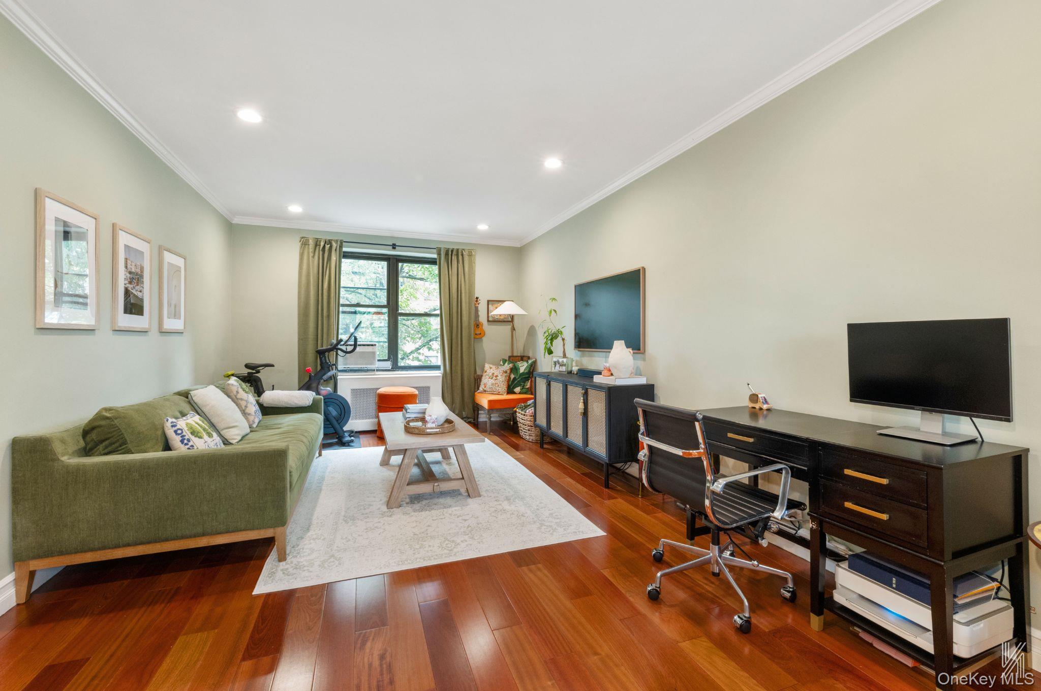 This beautifully renovated one-bedroom unit impresses with its crown moldings, cherry hardwood floors, and arched doorways. The crisp, clean paint, recessed lighting, and modern fixtures throughout create a cohesive and inviting atmosphere. Upon entering the condo, you will notice two large closets in the foyer, which are perfect for storing coats, shoes, and other items. Additionally, there is a double-wide closet in the hallway near the bathroom, ensuring that storage never becomes a concern.The spacious living room and dining area feature East and West-facing windows, providing a delightful cross-breeze and plenty of natural light. The double-wide window in the dining area overlooks the beautifully maintained back courtyard. This expansive space is ideal for entertaining and can comfortably accommodate a table for six. Two pendant lights hang above the half-wall pass-through breakfast bar, which features charming beadboard paneling.In the kitchen, you will find a Frigidaire Gallery five-burner gas stove with a microwave above it. Light wooden cabinetry extends to the ceiling, offering ample storage above the quartz countertops, which showcase elegant grey and gold veins. The vertical subway tile backsplash enhances the overall sophistication of the space.The bedroom boasts an oversized window that floods the room with light and overlooks a serene, tree-lined street. This space can easily accommodate a queen-sized bed, a vanity or desk, as well as a dresser and side tables.The windowed bathroom features floor-to-ceiling tile with a horizontal accent stripe in blue, grey, and bronze. The glass-enclosed shower/tub combination is equipped with Allen and Roth fixtures and a rain shower head. The dark blue painted cabinets beneath the sink provide additional storage and add a pop of color.Garden Bay Manor is a well-maintained condo complex that spans several square blocks in the highly desirable Upper Ditmars/Astoria Heights neighborhood. It is known for its beautifully landscaped grounds and low common charges and annual real estate taxes. Street parking is plentiful, and various transportation options, including the M60, Q69, and others, are nearby. Shops, cafes, restaurants, and LaGuardia Airport are just minutes away.