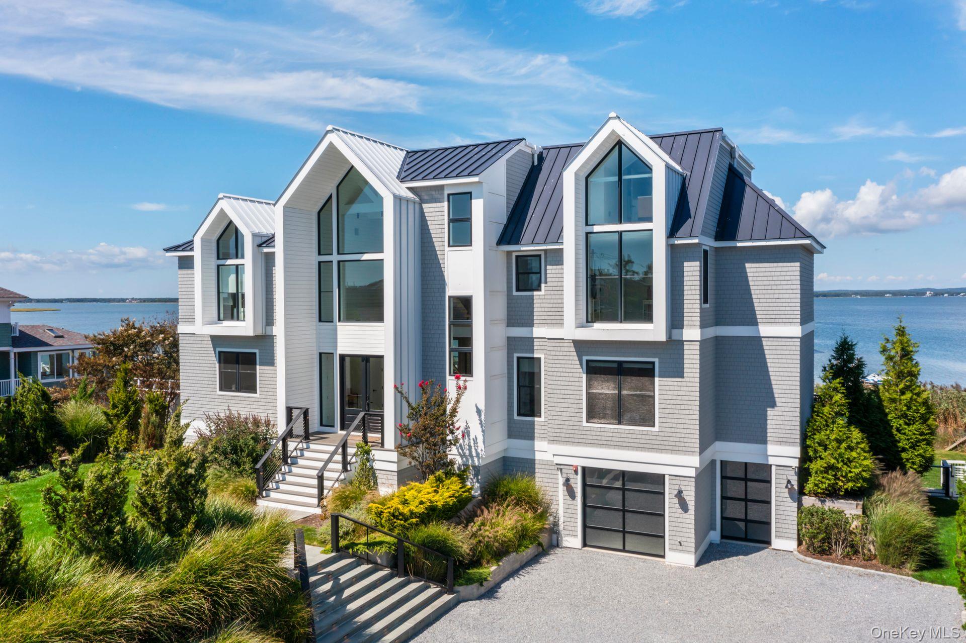 Discover Coastal Elegance at its Finest in Westhampton Dunes Sitting gracefully on 105 feet of open bayfront, this stunning residence epitomizes the pinnacle of modern luxury and design. Crafted with meticulous attention to every detail, this 5-year-young home spans 5, 200 sq. ft. across three levels of impeccable living space, offering unparalleled views of Moriches Bay. From the moment you enter the soaring 30-foot foyer, you&rsquo;ll be greeted by an open, sunlit layout that blends coastal charm with sophisticated modernism. The spacious living room features a gas fireplace and walls of oversized glass doors, seamlessly merging the indoor spaces with the bay views beyond. A chef&rsquo;s kitchen, outfitted with Thermador appliances and an integrated Gaggenau cooktop with Teppanyaki griddle, offers the perfect setting for culinary creativity. Dual ovens and dishwashers ensure that every entertaining occasion is met with ease, while radiant-heated tile floors on the first level add an extra layer of comfort and luxury. In addition, a media room/den provides a cozy retreat for movie nights or relaxing. All six ensuite bedrooms, with water views, are designed with privacy and relaxation in mind, providing perfect retreats for all. The primary suite is an oasis of tranquility with panoramic views of the bay, a private balcony, and a spa-like bath. Step outside to your own private paradise. The expansive waterside deck is ideal for both entertaining and relaxing, complete with a built-in BBQ and refrigerator for alfresco dining. The heated Gunite saltwater infinity pool, with a built-in spa, is positioned to take full advantage of the sweeping water views. A 156-foot catwalk, with a 12-foot ramp, leads to the brand-new 2025 floating dock. The home offers a seamless flow of indoor and outdoor spaces, making it ideal for both casual living and grand-scale entertaining. The attached 2.5-car garage and fenced backyard offer ample space for both storage and pets. Mature landscaping frames the property, offering privacy, while the meticulously maintained grounds ensure low-maintenance living at its finest. Located in a highly sought-after area, where new construction is rare, this exceptional home provides direct access to Moriches Bay for boating, fishing and all water sports, with the added benefit of ocean access just minutes away. The sunsets are remarkable!