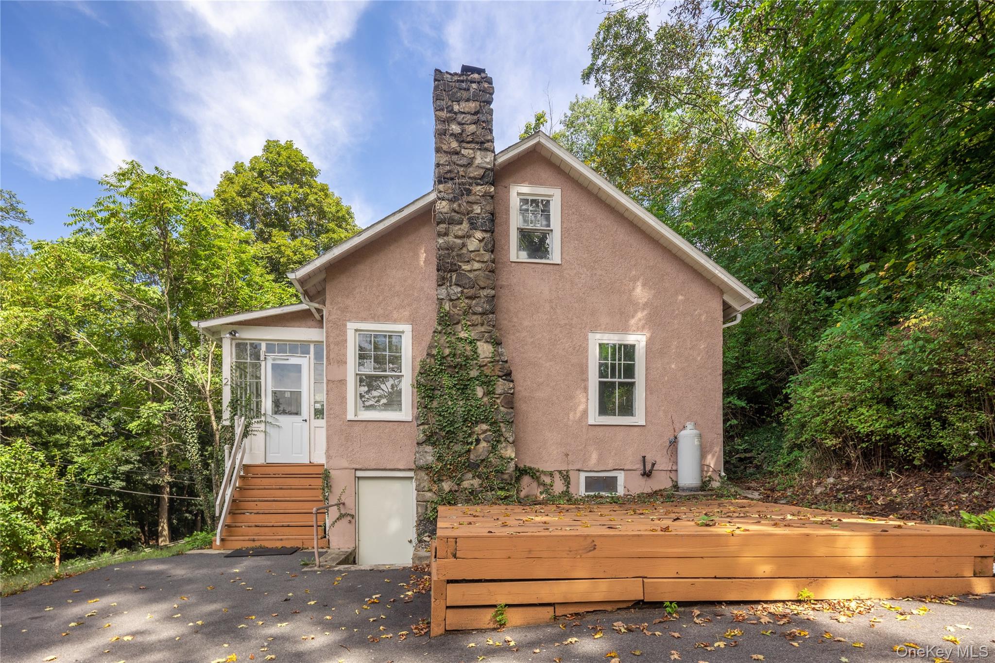 This conveniently located two-bedroom, one-bath stucco residence offers significant potential for improvement. Situated on a corner lot just minutes from the Metro North train station, major highways, shopping, and the charming hamlet of Croton Falls, it is ideal for commuters. Key features include hardwood flooring, a mantled stone fireplace, and an enclosed heated front porch adding additional living space. This property presents an excellent opportunity as a rental or year-round home for buyers seeking to add value through renovation.