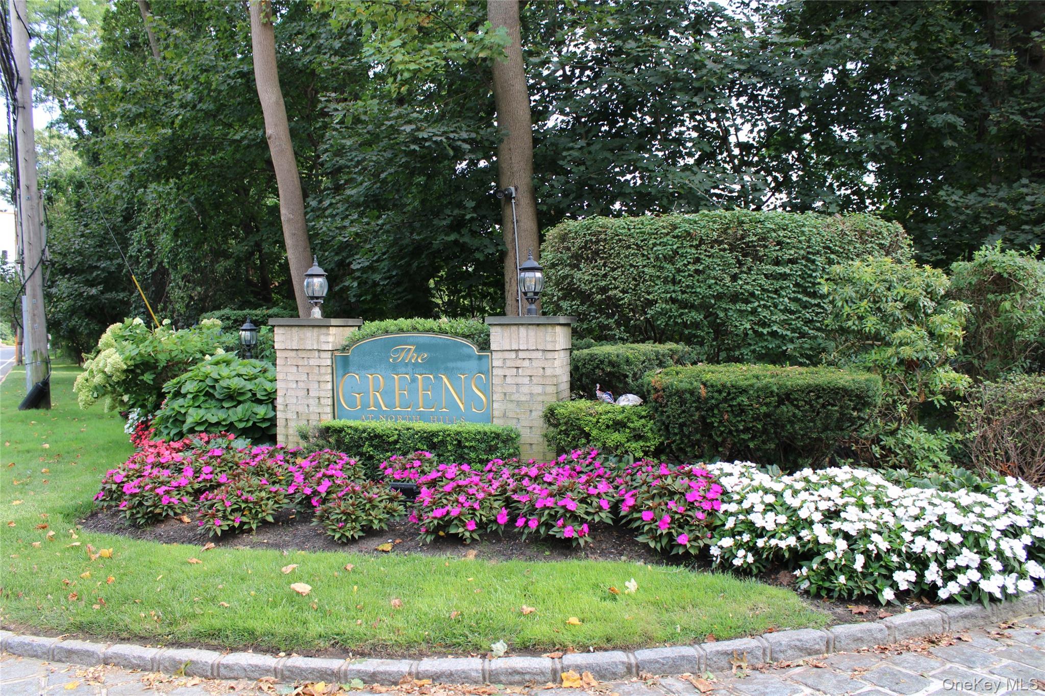 Beautiful condominium townhouse unit in The Greens condo development in the North Hills section of Manhasset, off of Shelter Rock Road. Large Primary Bedroom on the main level, with outfitted closets, and full en suite Primary Bath with stand-up shower and separate bathtub. Modern eat-in kitchen with large central island and open layout on the first floor, with high ceilings in the Living Room and Dining Rooms, and with two sets of sliding doors leading to the patio and spacious backyard. Well appointed Powder Room on the 1st level. Stacked electric washer/dryer units on 1st level. The 2nd level has a large Bedroom with windows and ample outfitted closets, and an adjacent Full Bath. There&rsquo;s also an unenclosed finished loft area at the top of the steps on the 2nd level, which can be used as a sitting area, den, home office, or library. Slate patio in the rear with a spacious backyard and plenty of trees for privacy. One car attached garage, with additional parking available in the driveway or in the adjacent common parking areas. Full basement with hot water heater, electric panel, utilities, and plenty of storage space. Utilities are all electric, no gas. The development also has a heated swimming pool and private Har-Tru tennis court. Easy access to highways, schools, railroad, highways, restaurants and shopping. Herricks School District. Board Approval Required. Property being sold AS IS.