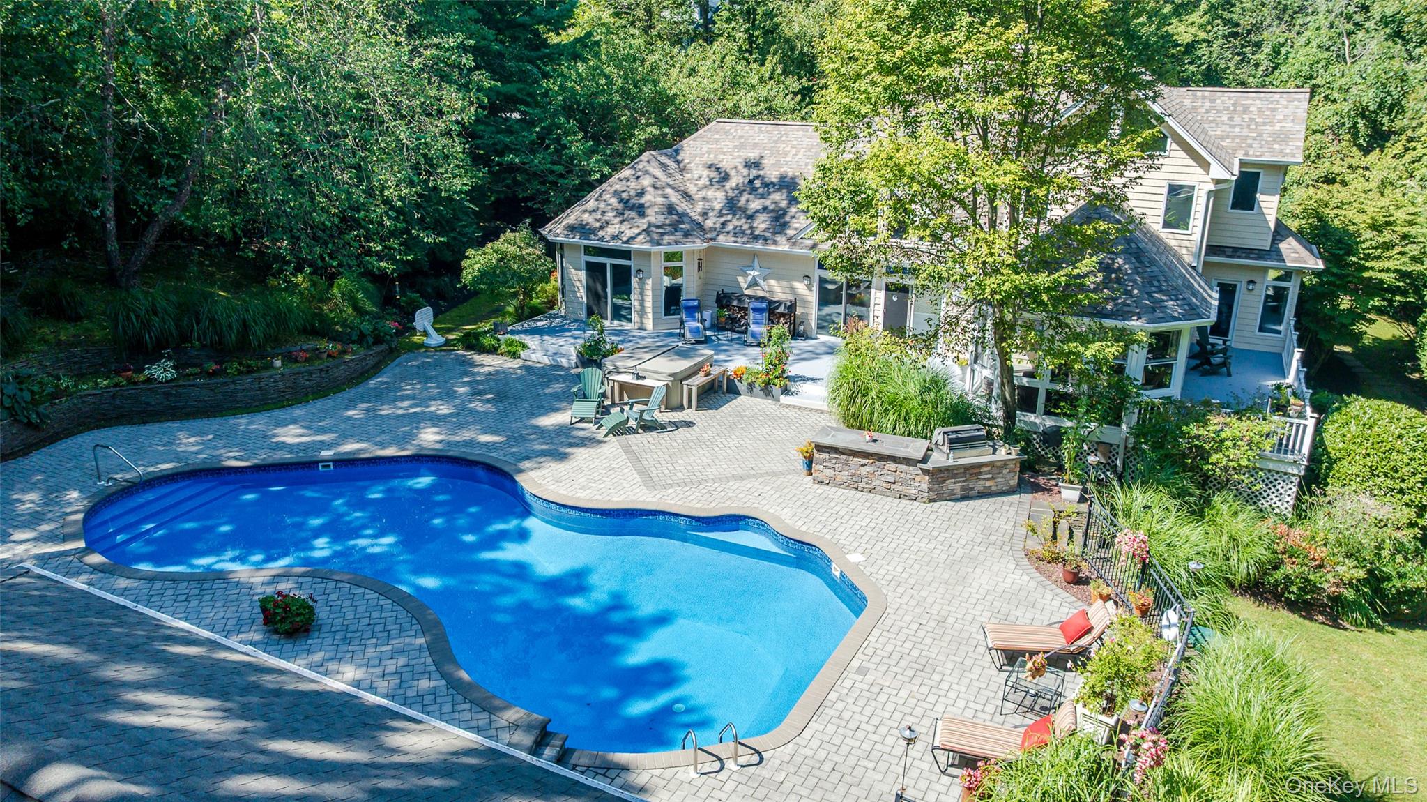 Experience North Shore Living at Its Finest. This stunning residence blends elegance, comfort, and resort-style amenities. This truly spectacular backyard is a private oasis with a heated pool, hot tub, custom pavers, adorned with fieldstone walls & professional landscaping, a built-in BBQ area, and a pool house equipped with a full kitchen, bathroom, CAC, heat, and covered patio. Stone steps lead to a parklike side yard with an additional garage beneath the pool house. Inside, the grand foyer opens to a living room with soaring ceilings, a dramatic two-sided quartzite fireplace, and walls of glass with transom windows framing backyard views. The primary suite offers deck access, two walk-in closets, and a spa-inspired bath with Jacuzzi tub, oversized shower, dual sinks, and radiant heat. The gourmet kitchen features a quartzite island, Sub-Zero refrigerator, Thermador oven, wine/beverage cooler, walk-in pantry, and breakfast nook. Off the formal dining room is a sun-filled four-season room that leads directly to the backyard deck, perfect for entertaining or relaxing with a view of the pool and gardens. The main level also includes a spacious laundry room, powder room with marble sink, and a two-and-a-half-car garage with direct access. Upstairs, a loft overlooks the living room, accompanied by oversized bedrooms, vaulted ceilings, custom built-ins, and sun-drenched adjoining rooms with skylights. The lower level offers a finished recreational area plus storage, utilities, and a wine room. Additional upgrades include: New: 50 year architectural roof, pool liner & heater, central vacuum, hot water heater, french drain system. Set in the desirable Shoreham-Wading River Central School District, this home offers the perfect balance of small-town charm, natural beauty, and modern convenience located just minutes from Long Island Sound beaches and perfectly situated at the gateway to North Fork wineries. Enjoy the Wildwood State Park nearby with hiking, biking, camping, and proximity to golf courses, and local farms. Wading River has it all, making this home not just a residence, but a lifestyle!