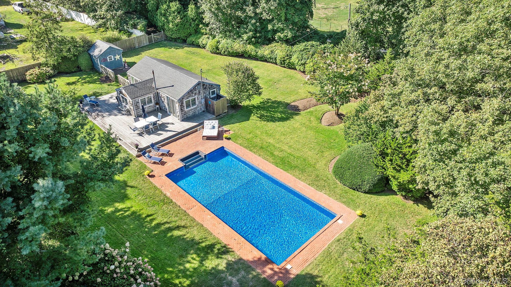 Privately situated & set back from the road, this charming East Hampton cottage features over 1/2 an acre of cleared, luscious property. The 2-bedorom, 1-bath pied-a-terre is close to all, just 100 yards from the famed Round Swamp Farm and 2 miles from East Hampton&rsquo;s Main Street. Inside, the kitchen is well-appointed with granite countertops, a GE natural gas range, and a full suite of Frigidaire appliances, including dishwasher & stackable washer and dryer. The living room and one of the two bedrooms open directly to the back deck, blending indoor-outdoor living. Hardwood floors and shiplap walls create a welcoming, coastal aesthetic, while recent upgrades-including custom window treatments (2024) and new Andersen windows (2025)-enhance comfort and efficiency. Central air, forced hot air heating, and natural gas utilities provide reliable year-round comfort. Step outside to a private backyard oasis, complete with a 20x40 heated pool, outdoor shower with hot and cold water, and a spacious, wrap around wood deck-perfect for entertaining. The cleared property is fully fenced, irrigated, and includes a permitted -750SF potting shed. With ultra-low annual taxes of just $3, 870.44 & years of successful rental history, this property offers exceptional value rarely found in East Hampton.