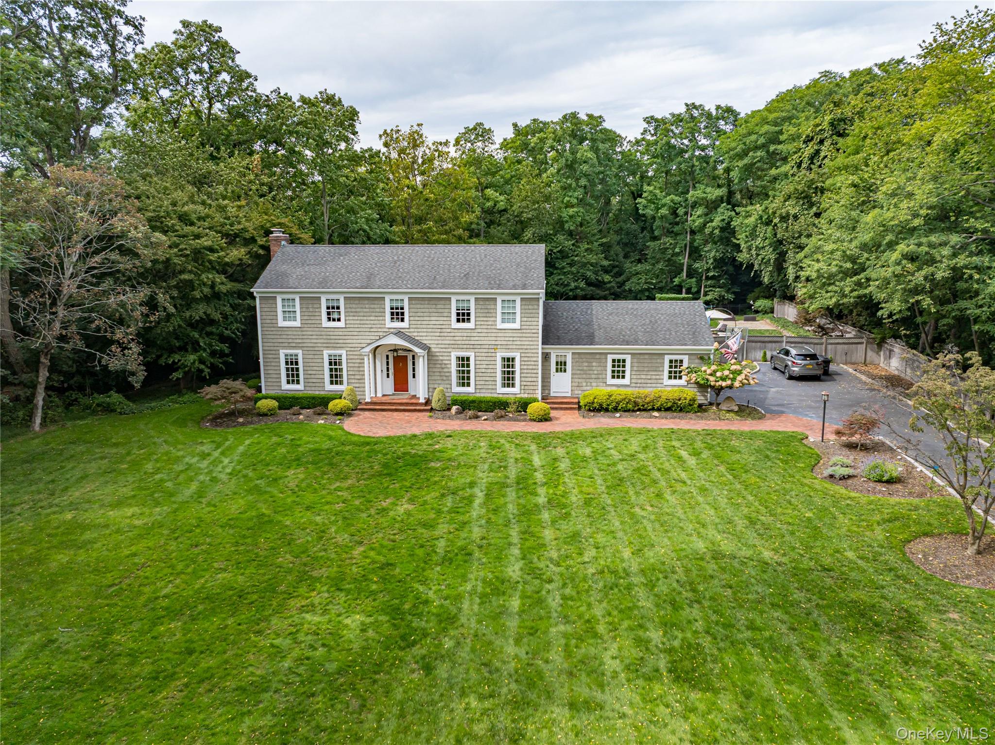Set back from the road, this expanded and spectacular updated classic colonial style home offers a beautifully landscaped and manicured property. A meticulously maintained, entertainer&rsquo;s dream home complete with an impressive yard with a salt water pool, newer hot tub, natural stone and paver patios and Trex decking. Surrounded by mature trees to ensure complete privacy while you enjoy the yard space. The custom chef&rsquo;s kitchen has timeless features from the travertine floor tile, the large center island, beautiful hard wood cabinetry, vaulted ceilings, granite countertops and the bumped out kitchen dining nook that is flooded with natural light. The warm and welcoming great room off the kitchen has a charming brick fireplace and hardwood flooring. The rear wall has French doors to the deck, full length windows and transom windows to the vaulted ceiling to allow in daylight. While keeping traditional in a colonial layout, this home has an additional room on the first floor with its own bathroom ensuite, could be a 5th bedroom, office, library or playroom. The gleaming hardwood flooring continues on the entire first floor into the main entryway, formal living room and formal dining room both have custom woodworking and moldings. Four bedrooms upstairs, hall bathroom is newly updated. Primary bedroom with massive walk in closet and ensuite spa inspired bathroom with a balcony that overlooks the yard. Pool heater and driveway are new. Recently converted to public water, no longer on well water utility. There is a generator and a full unfinished basement for plenty of storage. This is more than a home â€” itâ€™s a private retreat, perfect for those seeking space, style, and sophistication in a highly desirable location within the highly regarded Three Village Central School District.