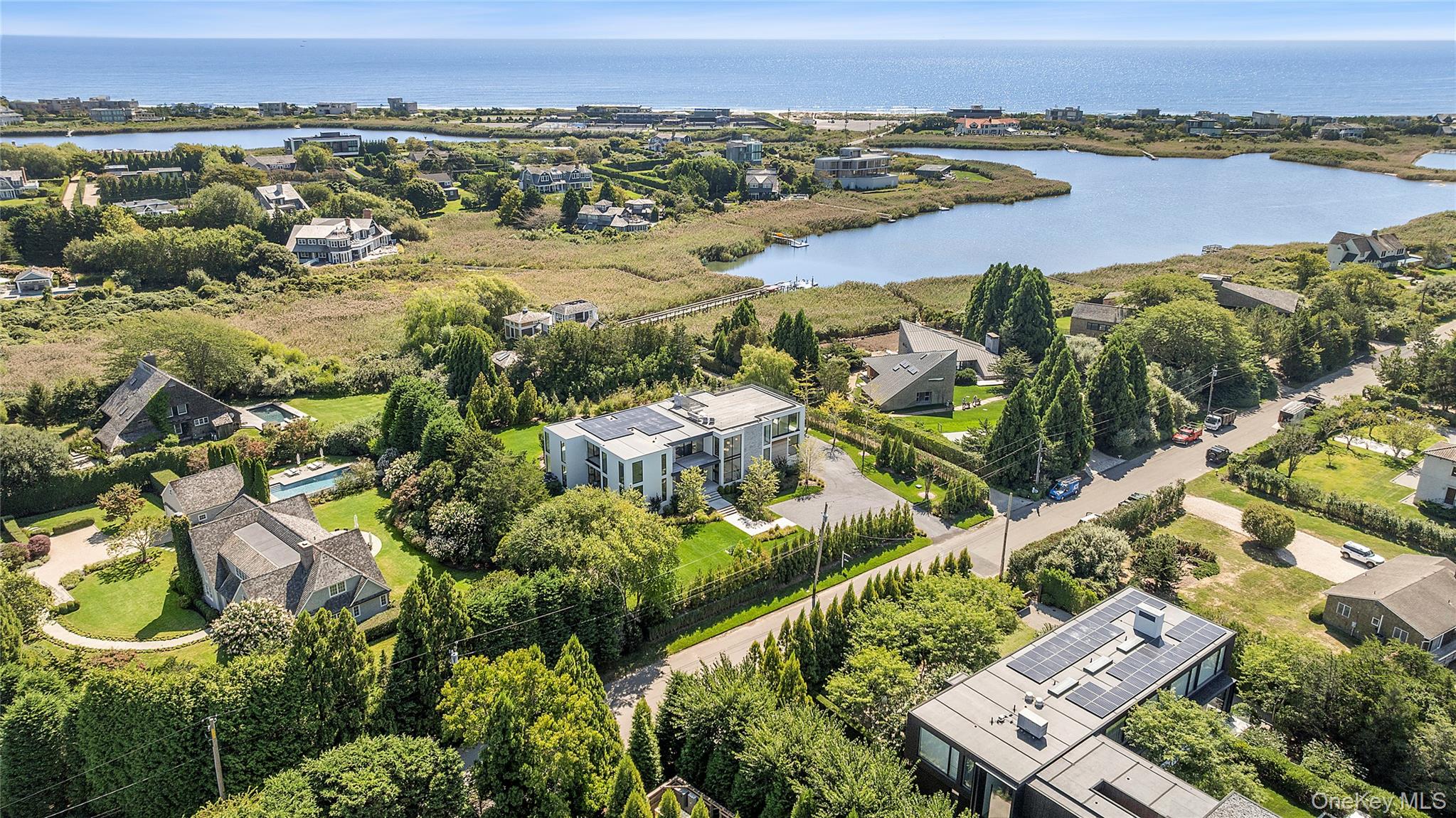Perfectly positioned south of the highway in Bridgehampton, this architectural showpiece sets a new benchmark for modern Hamptons living. Designed by McDonough & Conroy and brought to life by Hampton Builders, Inc. and Fineo Development Group, the residence blends sophisticated design with effortless functionality. Interiors curated by Leslie Norton Fineo of LNF Interiors and landscape design by Dean Gomolka enhance the homeâ€™s clean aesthetic, with Chris Mead of English Country Home completing the vision through expert staging.The exterior presents a refined palette of limestone, stucco, and custom mahogany siding, while walls of glass frame sweeping views of the ocean, bay, and Mecox Pond. Inside, 7, 800&#177; square feet of living space are arranged with an open, modern flowâ€”bathed in natural light and curated with meticulous attention to detail.The main level centers around a stunning chefâ€™s kitchen with dual islands, marble finishes, and top-tier appliances, complemented by a separate catering kitchen. Expansive living and great rooms feature dual-sided fireplaces, seamlessly connecting to the outdoor entertaining spaces. A formal dining room, en suite guest suite, junior primary with terrace, mudroom, and pool cabana with full bath complete this level.Upstairs, the primary suite is a true retreat, offering a private sitting area, spa bath, oversized custom closet, and a private terrace. Three additional en suite bedrooms, a second laundry, and rooftop access expand the lifestyle offerings, where an expansive roof deck affords panoramic ocean-to-bay vistas.Outdoors, the amenities are equally exceptional: a 20&rsquo; x 40&rsquo; infinity-edge heated gunite pool with in-pool spa, an outdoor kitchen, and sun-drenched patio framed by lush landscaping. A three-car garage and a private 0.92&#177; acre cul-de-sac setting complete this estate.Just moments from world-class beaches, vineyards, and Bridgehamptonâ€™s premier shopping and dining, this residence is a rare opportunity to own a south-of-the-highway sanctuary that blends cutting-edge architecture with timeless Hamptons luxury.