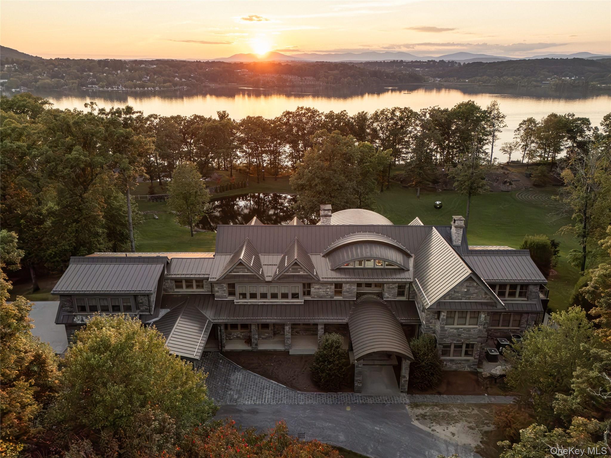 Stonecrest on the Hudson is a stunningly designed home on 16 inspiringly landscaped acres with extensive views of the river and the Catskills. A creation of stone, metal, and glass, the home, though imposing, inhabits its environment with seamless grace and is curated for comfort and meditative living. Many exquisite features make Stonecrest one-of-a-kind, impossible to duplicate. Upon approach, visitors notice the striking geometric roof lines and large portico. Inside, the home is open to light and nature through windows and soaring walls of glass. In the great room, forty-foot ceilings, a floor-to-ceiling stone fireplace surround, and curved transoms atop doors and windows make entry into Stonecrest a breathtaking experience. At the same time, there are many private spots for contemplation and quiet reflection that balance the grandeur of this remarkable home.In the south wing are a chefâ€™s kitchen with butlerâ€™s pantry and a formal dining room that opens to a bluestone terrace. Top of the line appliances, honed granite countertops, and double sinks and dishwashers ensure that anything can happen in this room, from an afternoon snack to a formal dinner for 30 people. The butlerâ€™s pantry has a second subzero refrigerator, a wine cooler, and sink. Also on this side of the house is an all-season sitting room and a mud room with its own covered portico for deliveries and access to the 3-car garage.On the north end of the home is a hallway art gallery, a private deck, an en suite guest bedroom, and best of all, a hidden library awaiting behind a secret door, with floor to ceiling windows, a fireplace, access to a private bluestone patio, and views of the river.The second floor can be reached by one of two gracious open stairways. A wide walkway that overlooks the great room extends the length of this second level. At one end is the primary suite that includes a private deck, a walk-through closet with separate dressing rooms and vanity space, and a spacious bathroom with jacuzzi and glass-bricked shower. The primary bedroom has windows on both sides with views of the river and sloping lawns. Next door is a second en suite bedroom that could also serve as a sitting room, den, or office.At the south side of the second story are two more en suite bedrooms, a media room, and entrance to an apartment annex with an open concept kitchen and living space, bedroom, and full bath. Perfect for employees or guests, this cozy space can be accessed from the back staircase for added privacy.On the lowest floor, a walk-out basement, an enormous space for creative pursuits, has easy access from inside or outside the home. Ample windows, a surround-sound system, and generous storage make this area versatile and convenient. Also on this level is a theater room and a second laundry/utility room.This property as it exists today cannot be recreated. For example, directly above the Hudson River, there is a resort-style saltwater swimming pool with stone pool house that includes a full kitchen and gathering space. Current zoning laws do not permit this kind of design nowadays.Countless stunning gems throughout the property include a reflecting pool with firepit and river views, an amphitheater facing the Hudson, a quarter-mile spiral labyrinth with stone paths divided by wild thyme, and a Koi-stocked pond with falling water. Seating areas dot the edge of the property above the river where spending hours watching the ships go by becomes a tranquil act of meditation.Though the home is an easy distance from charming Hudson Valley towns like Rhinebeck and a one-minute drive to the Rhinecliff Amtrak station, Stonecrest on the Hudson is as private and lost to time as an enchanted kingdom