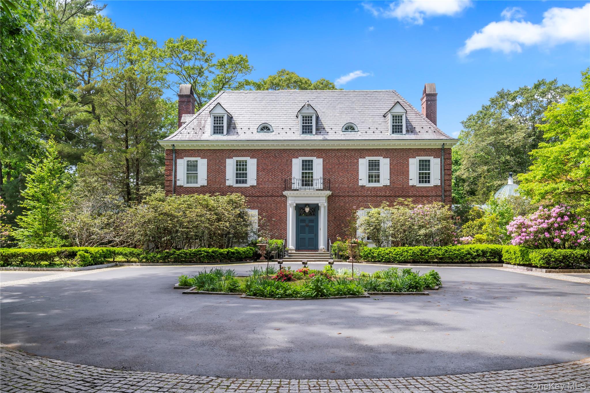 OLD WESTBURY. ICONIC COLONIAL-REVIVAL MANOR - Set on 2.26 private acres, this 1932 William Lawrence Bottomleyâ€“designed Colonial-Revival estate is distinguished by its remarkable architectural form. A four-story brick center residence is flanked by two sweeping first-floor wings that extend in a graceful semi-circle, creating both symmetry and a sense of grandeur rarely seen. Inside, timeless details include a dramatic spiral floating staircase, arched windows, intricate moldings, multiple fireplaces, and light-filled entertaining spaces. The home features 6 bedrooms, 5 full and 3 half baths, including a regal primary suite with study, dual baths, and walk-in closets. Elegant gathering rooms include a banquet-sized dining room, a solarium with wet bar and billiards area, and a stunning octagonal library with imported, fluted, conical ceiling and incredible acoustics. The grounds are equally impressive, offering a heated gunite pool with brick surround, outdoor kitchen, and a pool house with party room, kitchenette, and baths, a circular courtyard with 4 garage bays, and slate and copper roofing complete this one-of-a-kind estate. A must see!!