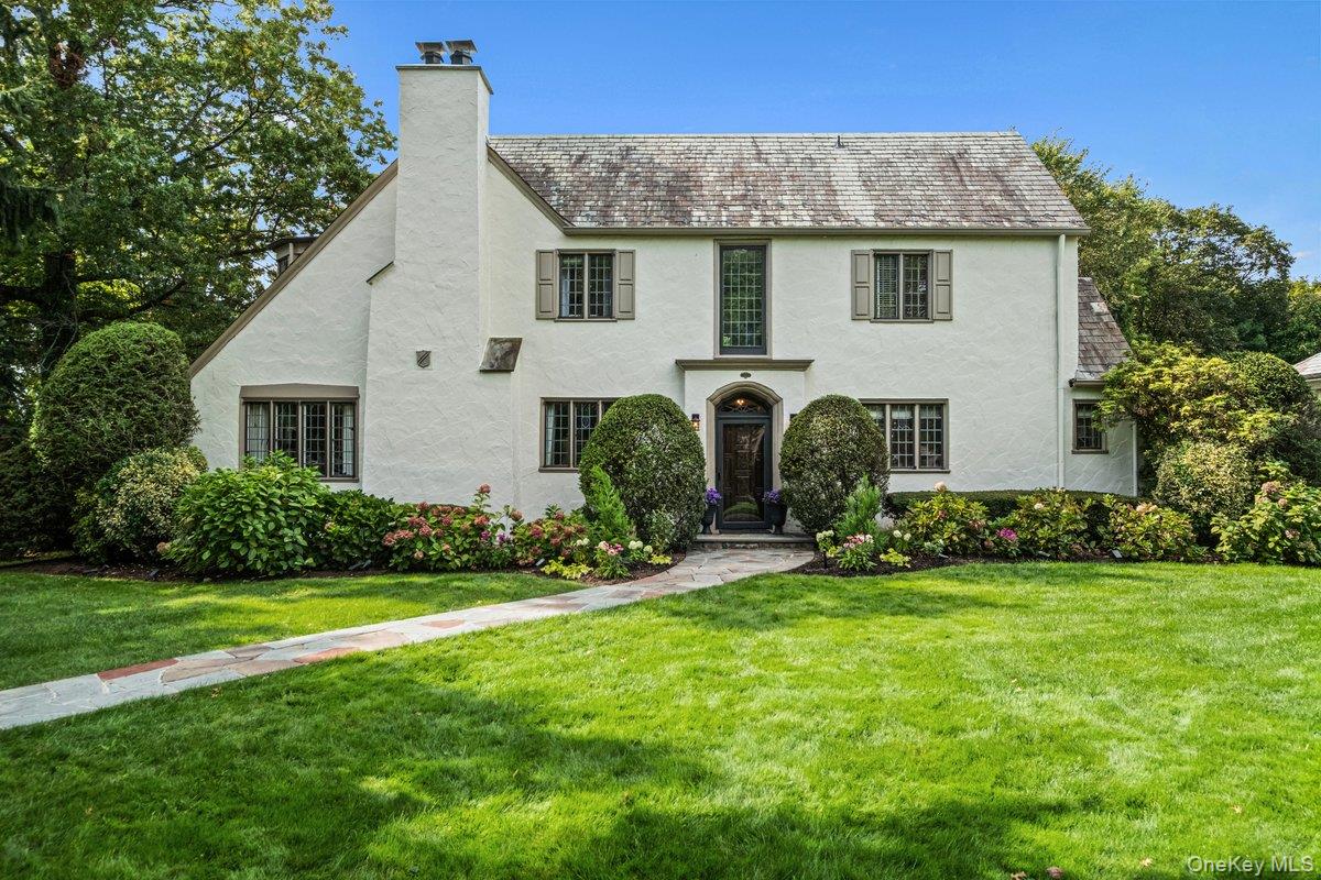 Modern vibe meets classic charm in this spectacular updated English Tudor, gracing over a third of an acre in one of New Rochelle&rsquo;s most sought-after locations. With magnificent curb appeal and stunning original architectural details perfectly paired with tasteful updates, it&rsquo;s easy to fall for this beauty. The gracious entry foyer opens to a breathtaking sunken living room with 12-foot ceilings, fireplace and remarkable original stained glass windows which have been artfully restored. The fabulous family room features skylights and wall to wall windows overlooking the gorgeous gardens, porch and patios. A formal dining room opens to the captivating grounds, seamlessly blending the indoor and outdoor entertaining space. Recently updated, the eat-in kitchen presents extensive cabinets, granite counters and new stainless steel appliances. The first floor is complete with a powder room as well as a coveted first floor bedroom with a beautiful ensuite bathroom. All bedrooms feature deep closets and all five bathrooms have been redone with designer touches. The spectacular primary bedroom features a sitting area, double closets and an ensuite bath with double sinks and a walk-in shower. There are striking original details at every turn, and this haven is as pristine as can be. Enjoy recessed lighting, handsome hardwood floors and three-zones of central air conditioning and heating. Home is wired for portable generator, a wireless ADT security system and boasts a two car garage with high ceilings, epoxy flooring and storage. Plus, the basement provides over 1000 sq ft of inviting bonus space. Nestled amongst mature trees and specimen plantings, the backyard is a private, tranquil oasis. All this, in a convenient location near shopping, restaurants, schools and worship. Just a 30 minute train ride to NYC.