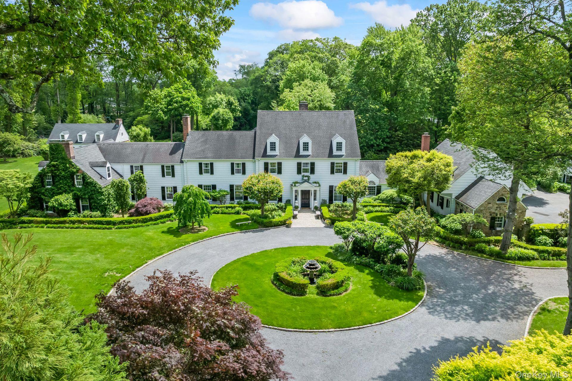 Set on 3.32 meticulously landscaped acres, this sophisticated and elegant Gold Coast jewel is a true luxury retreat. The home was designed by esteemed early 20th-century architect Mott B. Schmidt, who was highly regarded for his grand homes, and sought after by many high profile clients. A grand entrance welcomes guests, framed by stately arched trees that line the long, circular driveway. As they arrive at the main entrance, they are greeted by a beautiful fountain and lush gardens. Inside, the richly paneled foyer and wide pegged oak floors set the stage for exquisite architectural details, including a sweeping staircase and intricate custom millwork. The first floor offers a seamless blend of grandeur and comfort. The magnificent living room and banquet-sized dining room both feature elegant fireplaces, while the gourmet kitchen boasts a spacious center island and a bright breakfast room. A butlerâ€™s pantry adds convenience, and the library, adorned with built-in bookcases and a fireplace, offers a cozy retreat. Additional highlights include a sunroom, two en suite guest bedrooms, a first-floor washer/dryer, and a powder room. Oversized windows throughout the home provide breathtaking views of the lush grounds. The expansive primary suite is a private sanctuary, complete with a fireplace, spa-like bath, dressing area, and a large balcony overlooking the manicured gardens. This level also features four additional bedrooms with two Jack-and-Jill baths, two additional fireplaces, a gracious hall bath, a gym/bedroom, an office/bedroom, and a second-floor laundry room. The lower level offers an abundance of recreational space, including a playroom, arts and crafts area, and a full bath. The exquisitely landscaped grounds provide something for everyone, offering endless opportunities for relaxation and entertainment. The sunken gardens, originally designed by renowned landscape architect Robert Ludlow Fowler Jr., are a marvel to behold. They gracefully lead the way to a serene 20x50 saltwater gunite pool that is complemented by a spacious, elegant pool house. Sports enthusiasts will appreciate the lighted clay tennis court and a heated, enclosed outdoor structure, perfect for squash or basketball. Adding to the estateâ€™s appeal, a charming three-bedroom, two-bath guest cottage provides comfortable accommodations, while a three-car heated garage with a separate workroom ensures ample space for vehicles and storage. This extraordinary estate is a timeless masterpiece inside and out, seamlessly blending historic charm with modern refinement.