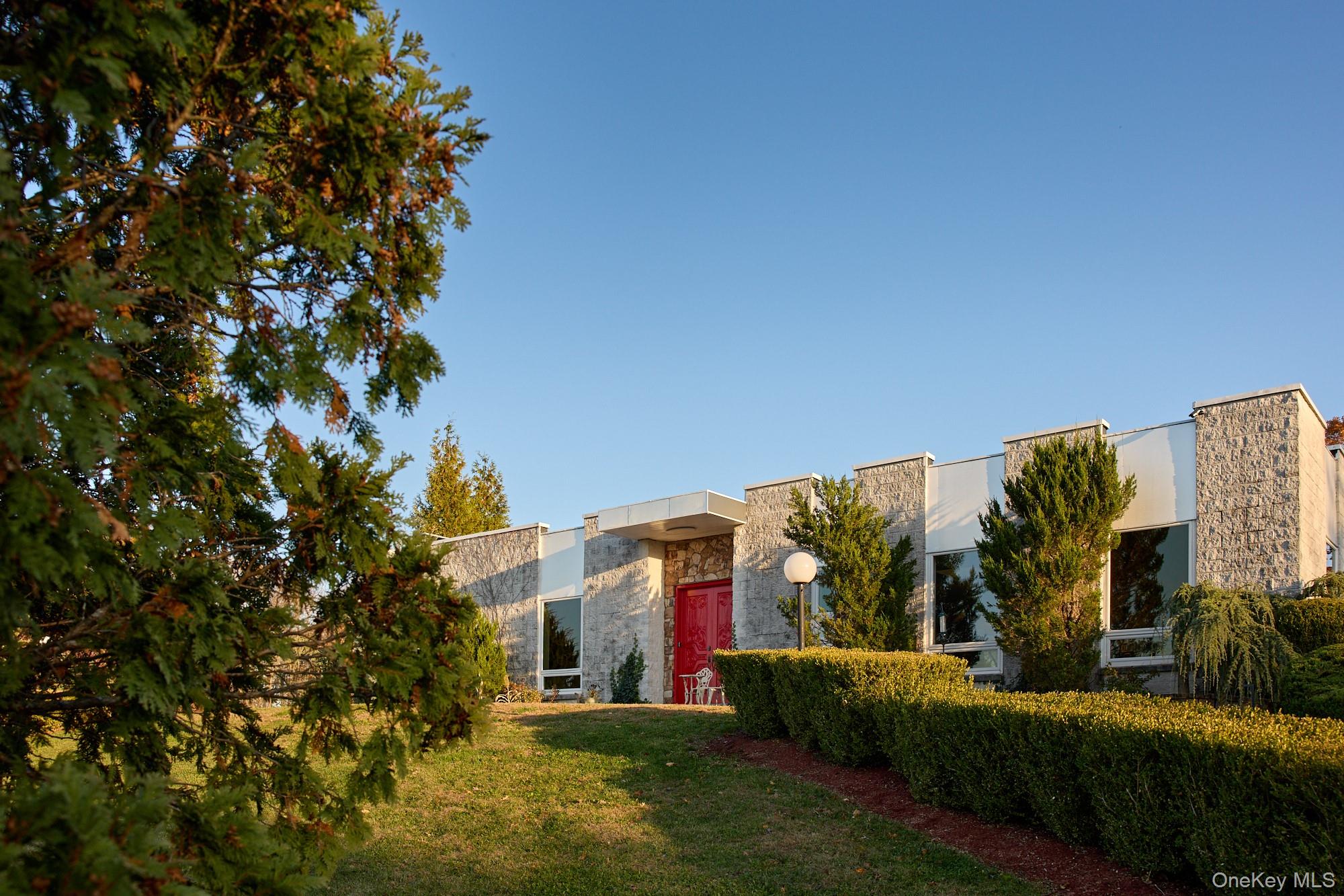 Palatial and modern, this flat roof contemporary on 7.4 manicured acres is truly one of a kind: private and spacious, with an indoor pool and spa, outdoor pool, and mountain views. The property has been thoughtfully landscaped with a style mirroring the home&rsquo;s structure--formal and balanced. Beautiful sights abound, gazing over the extensive lawns to the west and bucolic stone walls lining a neighboring field. Inside, the minimalist structure of this home provides a backdrop for a recent renovation which has brought all systems and finishes to flawless function and condition. There are polished concrete floors throughout the generous open floor plan, sky lights, expansive windows, and large fixed pane windows streaming sunlight from the pool area. For relaxation and exercise year-round, the indoor pool room is a sunny haven, with greenhouse style windows, a beautifully tiled indoor pool with integrated spa, enclosed shower, and seating area. A slider leads to a lovely outdoor dining patio area with a stone fire pit, and grassy lawn leading down to the fenced inground pool and gazebo. Both pools are saline treated, offering silky water and better air quality than traditional chlorine. The primary bedroom looks out to the peaceful koi pond garden with waterfall--very retreat-like--and opens to a sunroom with wood panelling and access to the patio. The ensuite bathroom is luxurious--soaking tub, rainfall shower, two toilet/bidet rooms--and leads to the full walk-in closet/dressing room. Industrial size and style define the kitchen, where one can truly cook for a crowd using the Vulcan 6 french plate and 24 griddle cooktop, double oven, commercial vent hood, Fagor dishwasher, three-compartment sink and disposal, and commercial fridge/freezer combo. The clean lines of the double height pantry enclose cabinets and drawers, and the oversized stainless steel island offers storage, a retractable center power outlet, and a leathered black granite top. Huge windows and dreamy views of the mountains make the kitchen a sweet place to linger over a cup of coffee. A beautiful stone fireplace draws the eye in the den, currently used as a game room, which can be closed from the main living area with a sliding door. Two additional, spacious bedrooms each with a full bathroom, round out the main level floor plan. The glass and steel staircase lead to the lower level, which includes an additional bedroom with ensuite bathroom, laundry room, second full bathroom, and a large recreation room currently housing a luxury car collection. A convenient private entrance and 2-car garage on this level open to a large finished parking area. Nest thermostats control the home&rsquo;s hybrid heating and cooling system to maintain comfort in every season. Luxuriously lit throughout, you&rsquo;ll find gorgeous chandeliers, fun aqua colored pool lights, and newly installed LED light fixtures with Lutron dimmers for precise control. Exterior lighting has been updated with LED driveway lights and bronze garden fixtures. This is a Hudson Valley home like no other - sited in proximity to colorful local towns like New Paltz, local apple farms and wineries, hiking and recreation in the Gunks, and 75 miles to NYC.