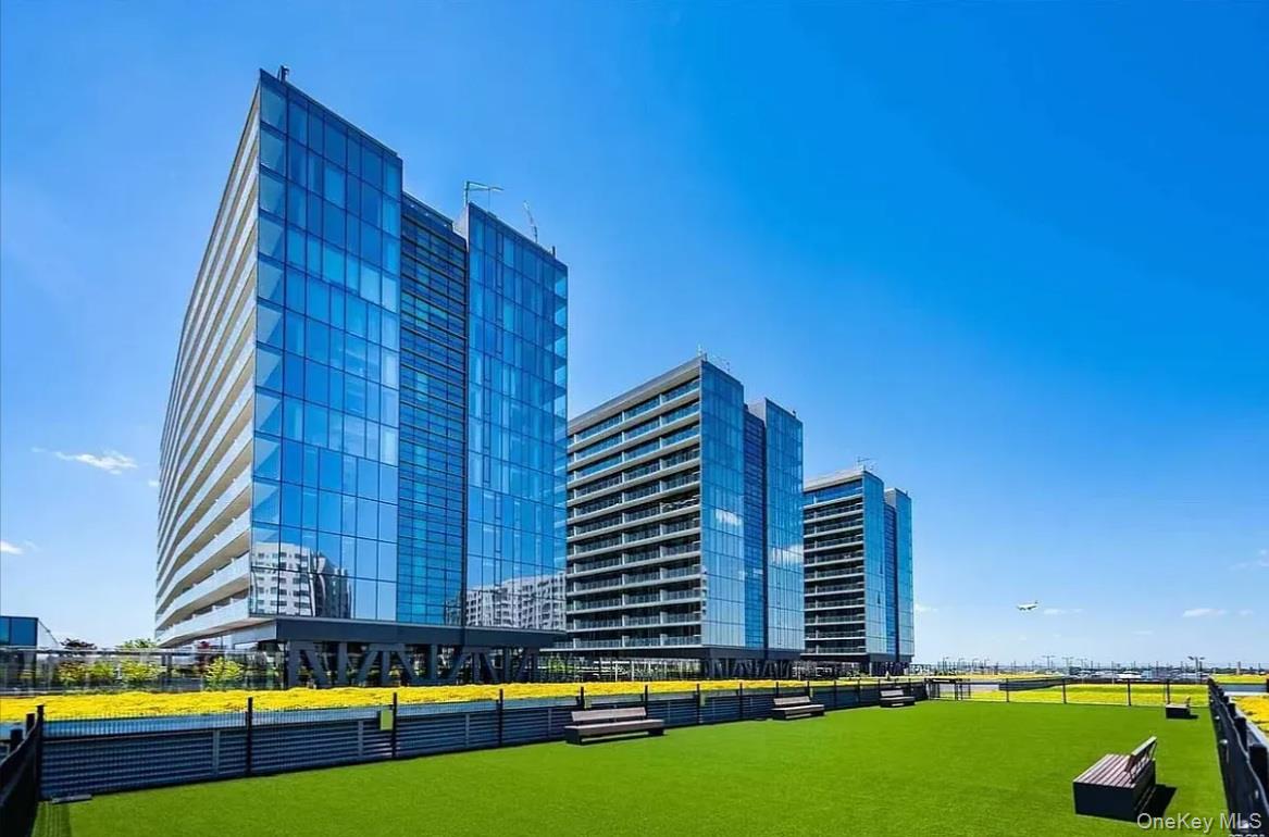 Welcome to this stunning one-bedroom, one-bathroom residence perched on a high floor, offering sweeping city and skyline views. Floor-to-ceiling windows flood the space with natural light, highlighting the elegant finishes and modern design throughout. The open layout includes a sleek kitchen with Bosch appliances, quartz countertops, and custom cabinetry. A spacious private balcony extends the living space outdoorsâ€”perfect for relaxing or enjoying the panoramic city and bridge views. The bright living area and serene bedroom offer comfort and style, complemented by a bathroom with premium finishes.Located in a full-service condominium with amenities including a fitness center, hot tub, residentsâ€™ lounge, in-door children&rsquo;s&rsquo; playroom, outdoor playground, tennis court, basketball court, dog park, and 24-hour doorman, this residence offers both luxury and convenience.Prime location: Situated directly above a lively shopping mall featuring BJâ€™s, Target, clothing stores, beauty shops, and sneaker retailers, everything you need is right downstairs. Just a 5â€“10 minute walk to the 7 train and LIRR, making commuting to Manhattan and other boroughs quick and effortless.