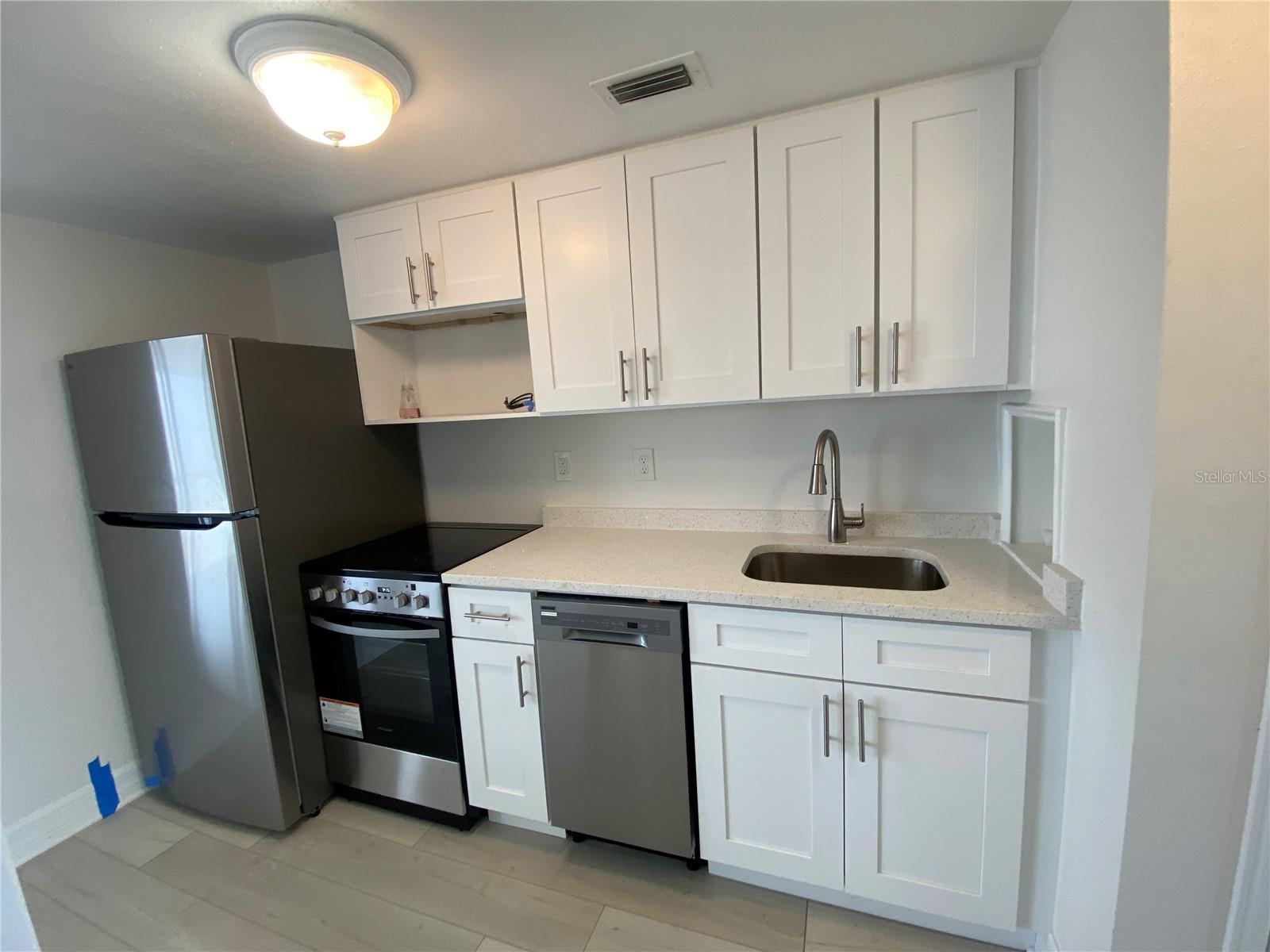 Your back is to the lavatory, view towards the kitchenette. (To the right is the HVAC closet with some extra storage space) Entrance door, out of view, to your right. All new appliances, cabinets & quartz countertop. Notice there is even a dishwasher???