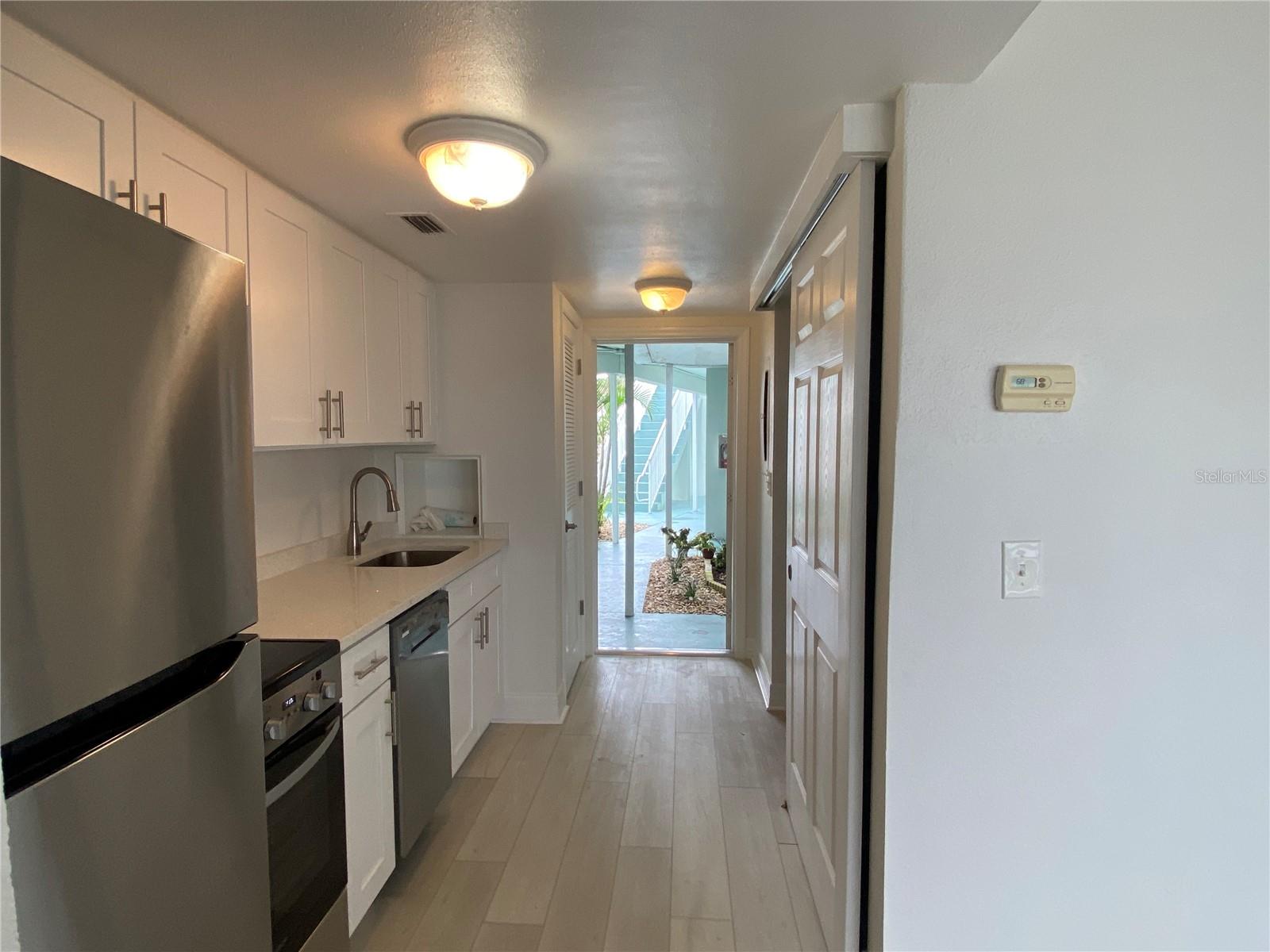 View of kitchenette towards the front door. The louvre door houses the newer HVAC closet. Across from the HVAC closet is the entrance to the lavatory, via barn door.