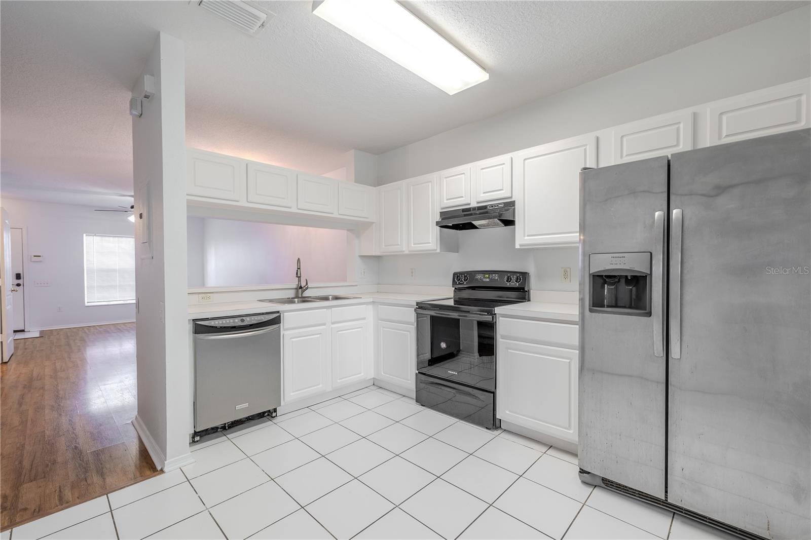Kitchen features ceramic tile flooring, stainless steel appliances including a French door refrigerator with ice maker and water dispenser, an electric range and sliding glass door to the private screened in patio.