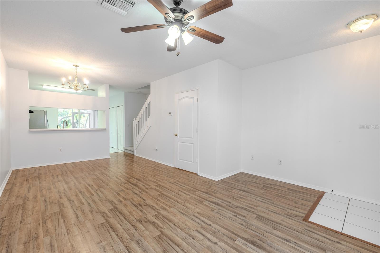 The Living room features neutral tones, wood laminate flooring, a ceiling fan with light kit and picture window.