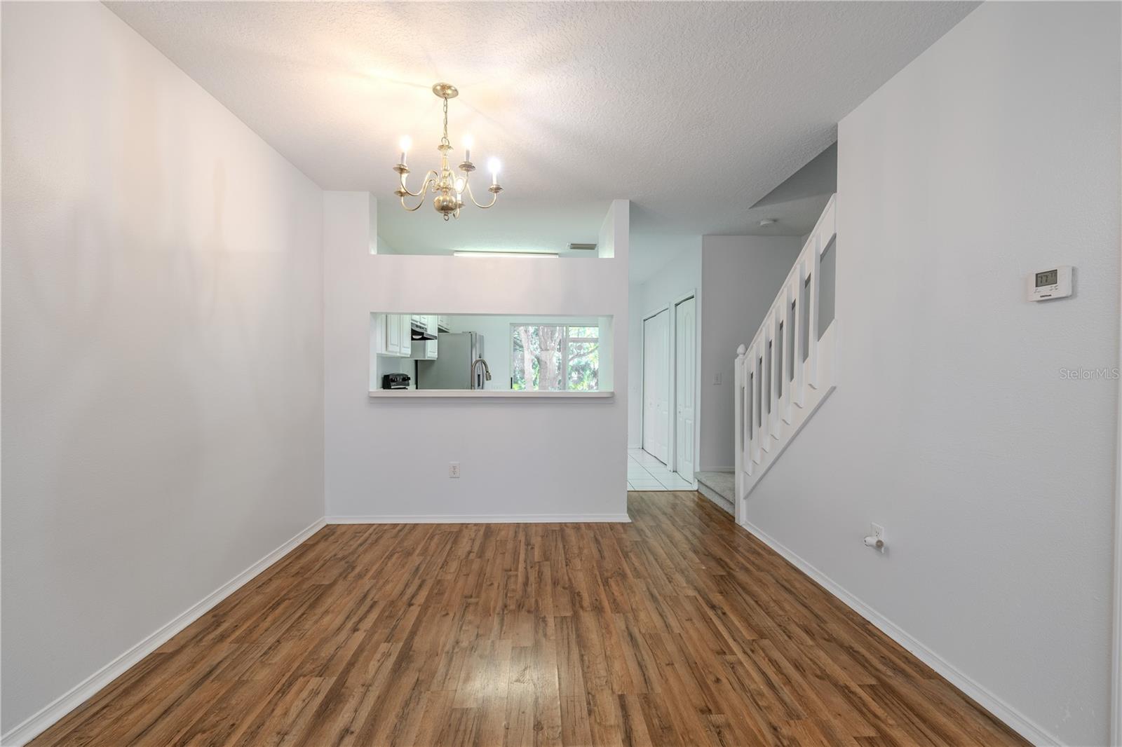 Dining room features wood laminate flooring, a 6 light chandelier and a convenient pass thru to the kitchen.