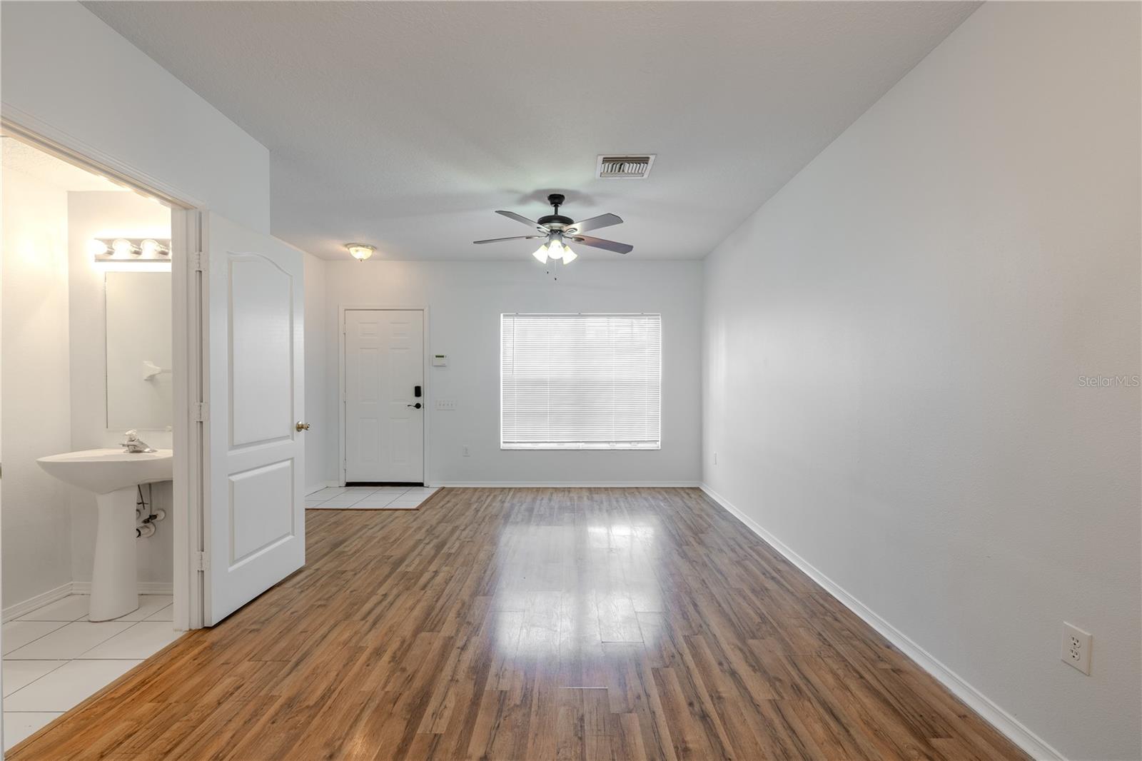 The Living room features neutral tones, wood laminate flooring, a ceiling fan with light kit and picture window.